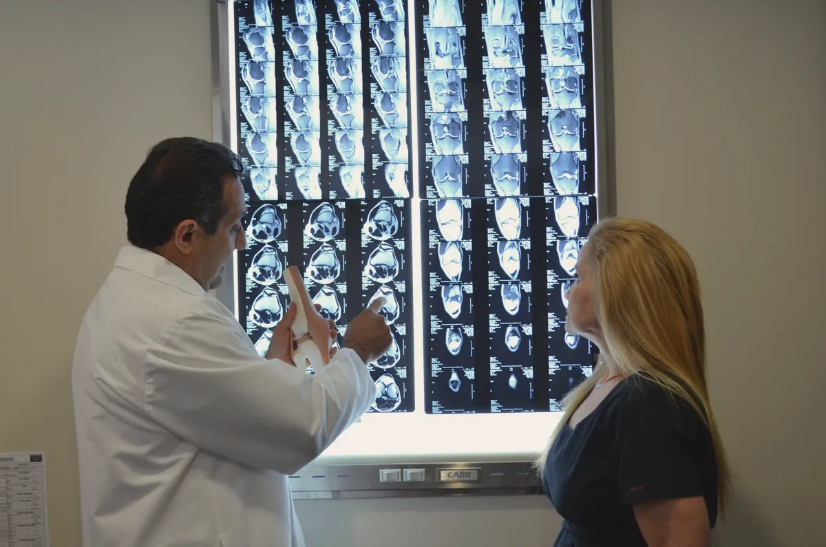 A physician reviewing imaging with a patient at a lightbox